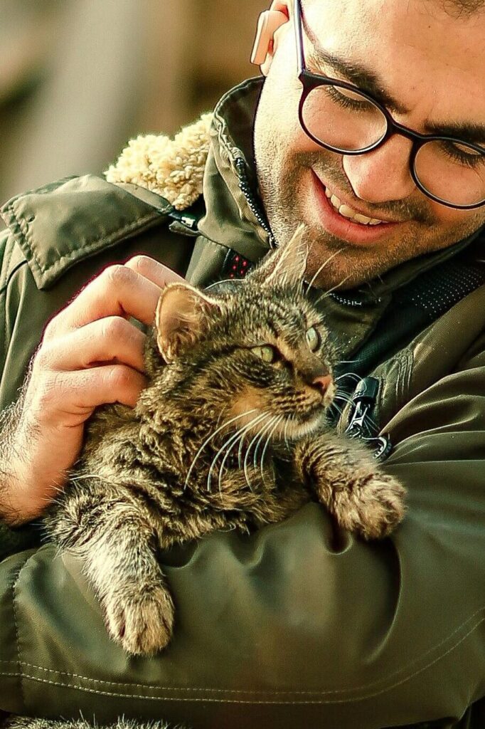 Man warmly embraces his cat amidst a backdrop of urban ruins, depicting resilience.